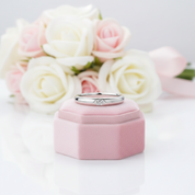 Silver ring in a pink jewelry box with flowers in the background