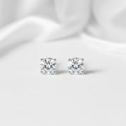 Pair of diamond stud earrings on a light fabric background
