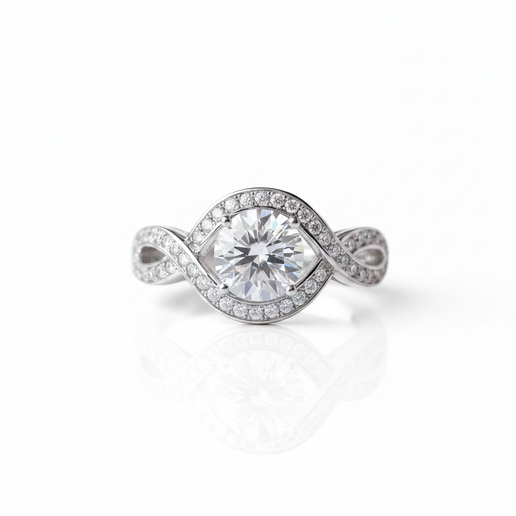 A silver-toned twist ring featuring a round brilliant-cut center stone surrounded by a halo of small pavé stones, with the band also paved with small stones, shown on a white background with a soft reflection.
