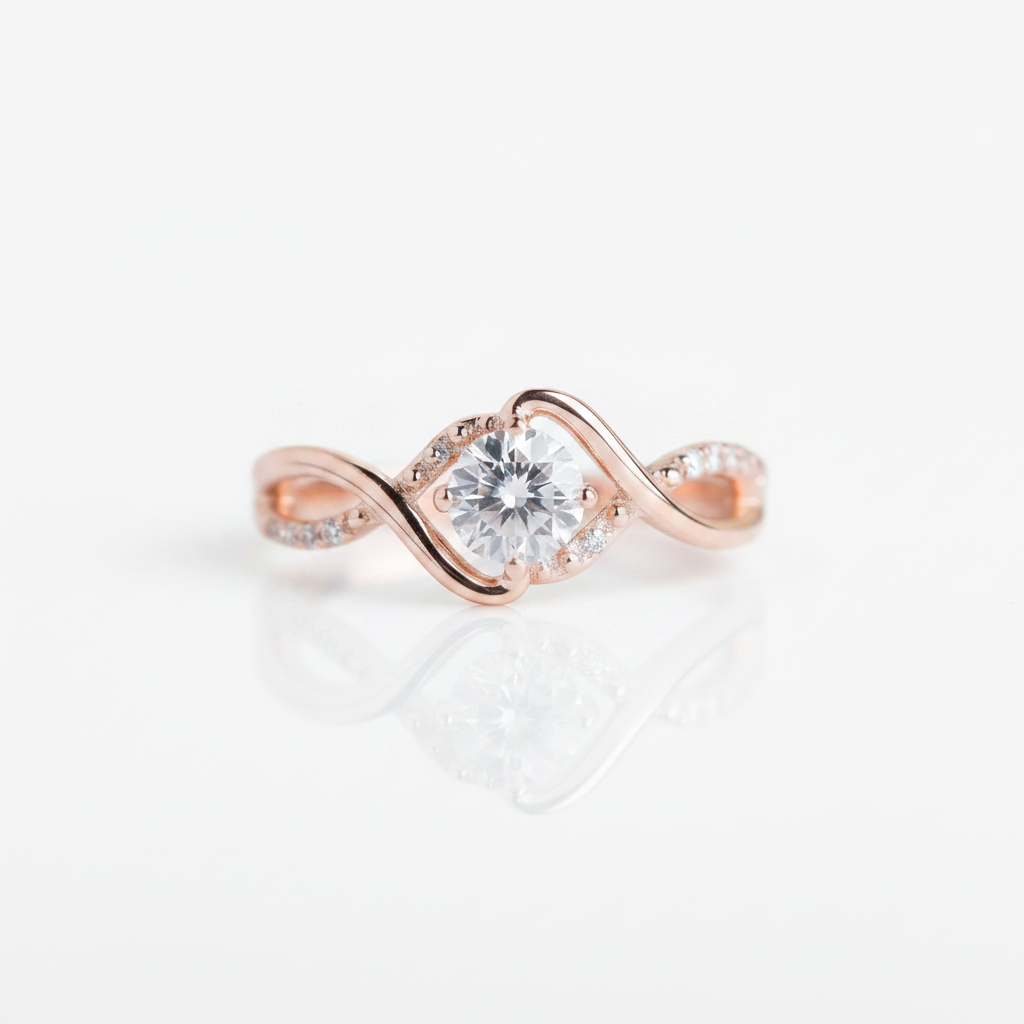A rose gold engagement ring with a round-cut clear center stone and small accent stones along the band, shown on a clean white background with a soft reflection below.