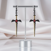 Sword-shaped earrings on a stand with a soft background