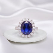 Ring with a blue gemstone and diamond halo on a white fabric background
