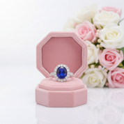 Ring with a blue gemstone in a pink box with flowers in the background