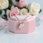 Rose gold necklace with diamond pendant on a pink jewelry box with flowers in the background