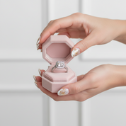 Diamond ring in a pink velvet box with flowers in the background