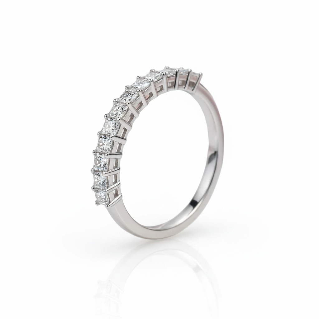 A silver-toned eternity ring featuring a row of princess-cut diamonds, shown on a clean white background with a soft reflection below.