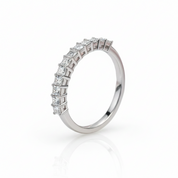 A silver-toned eternity ring featuring a row of princess-cut diamonds, shown on a clean white background with a soft reflection below.