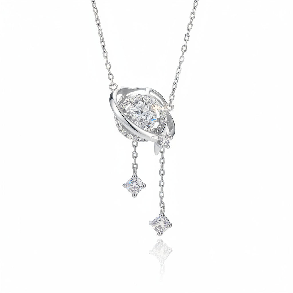 A silver-toned space-themed pendant necklace featuring a ring with a central clear gemstone, a small moon, and two dangling star charms, shown on a clean white background with a soft reflection.