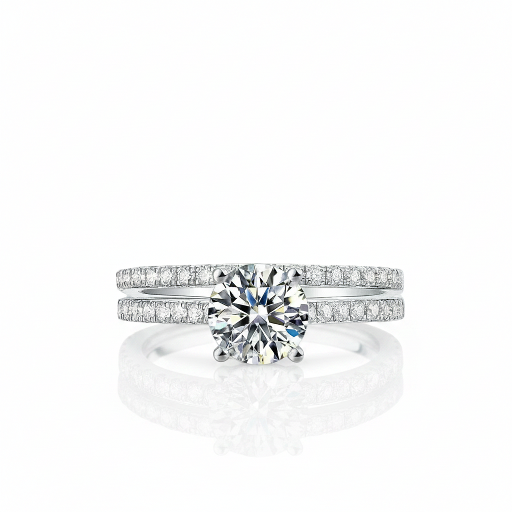 A silver-tone diamond ring set featuring a round-cut center stone and pavé-set bands, shown on a clean white background with a soft reflection below.