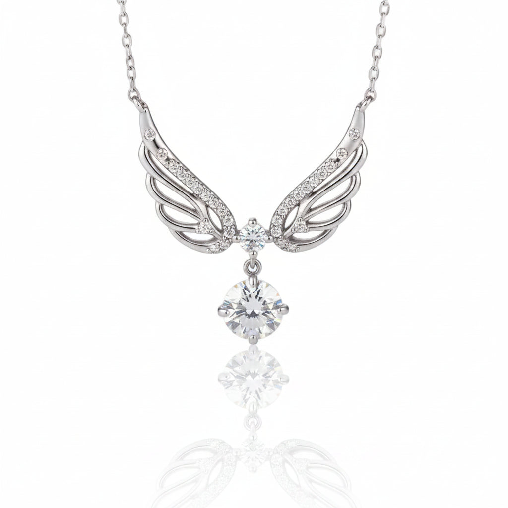 Silver angel wing pendant necklace with clear crystals, featuring a detailed wing design and a dangling clear gemstone, shown on a reflective white surface.
