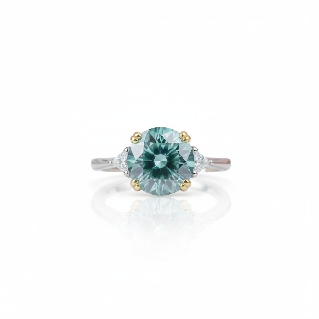 A center-stone ring featuring a round light blue-green gemstone in a four-prong setting, flanked by small clear side stones on a silver-toned band with gold accents, shown on a white background with a soft reflection.