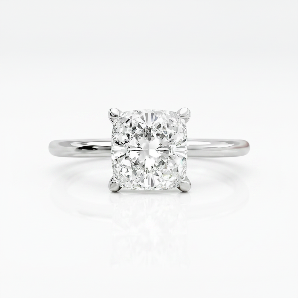 A radiant cut diamond solitaire engagement ring in a polished white gold or platinum band, centered on a clean white background with a soft reflection below.