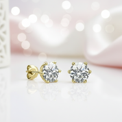 Gold diamond stud earrings on a soft pink background