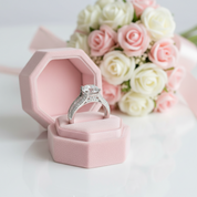 Silver ring in a pink jewelry box with flowers in the background