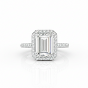 An emerald-cut halo ring featuring a central diamond surrounded by a double halo of smaller round diamonds, with a pavé band, set in a silver-colored metal on a white background.