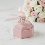 Pink diamond ring on a pink box with flowers in the background
