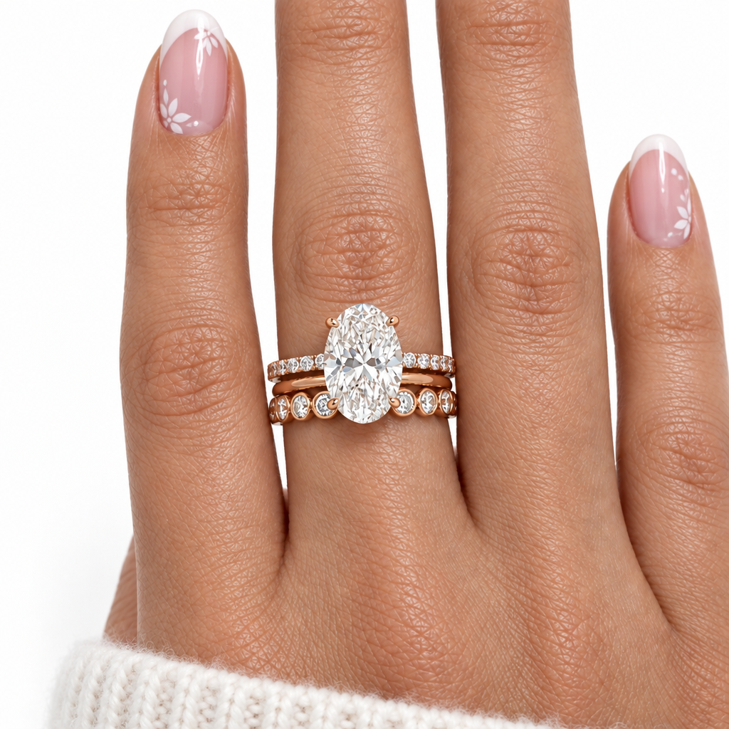 A close-up of a hand wearing a rose gold ring set featuring a large oval-cut diamond center stone with matching diamond bands, against a clean white background.