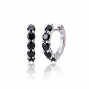 A pair of small silver huggie hoop earrings with a row of round black gemstones, shown on a clean white background with a soft reflection below.