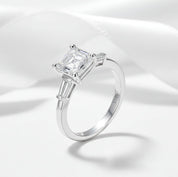 Silver ring with a large diamond on a white satin background