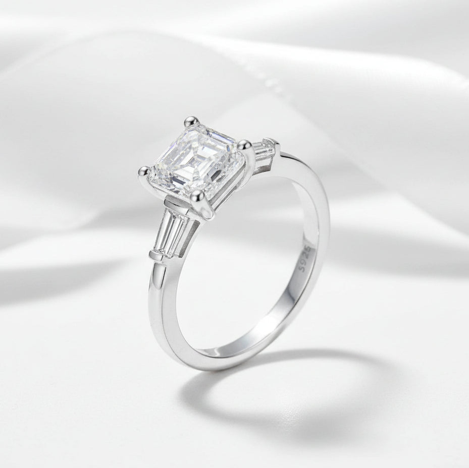 Silver ring with a large diamond on a white satin background