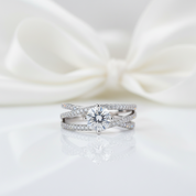 Silver ring with a diamond on a white satin background