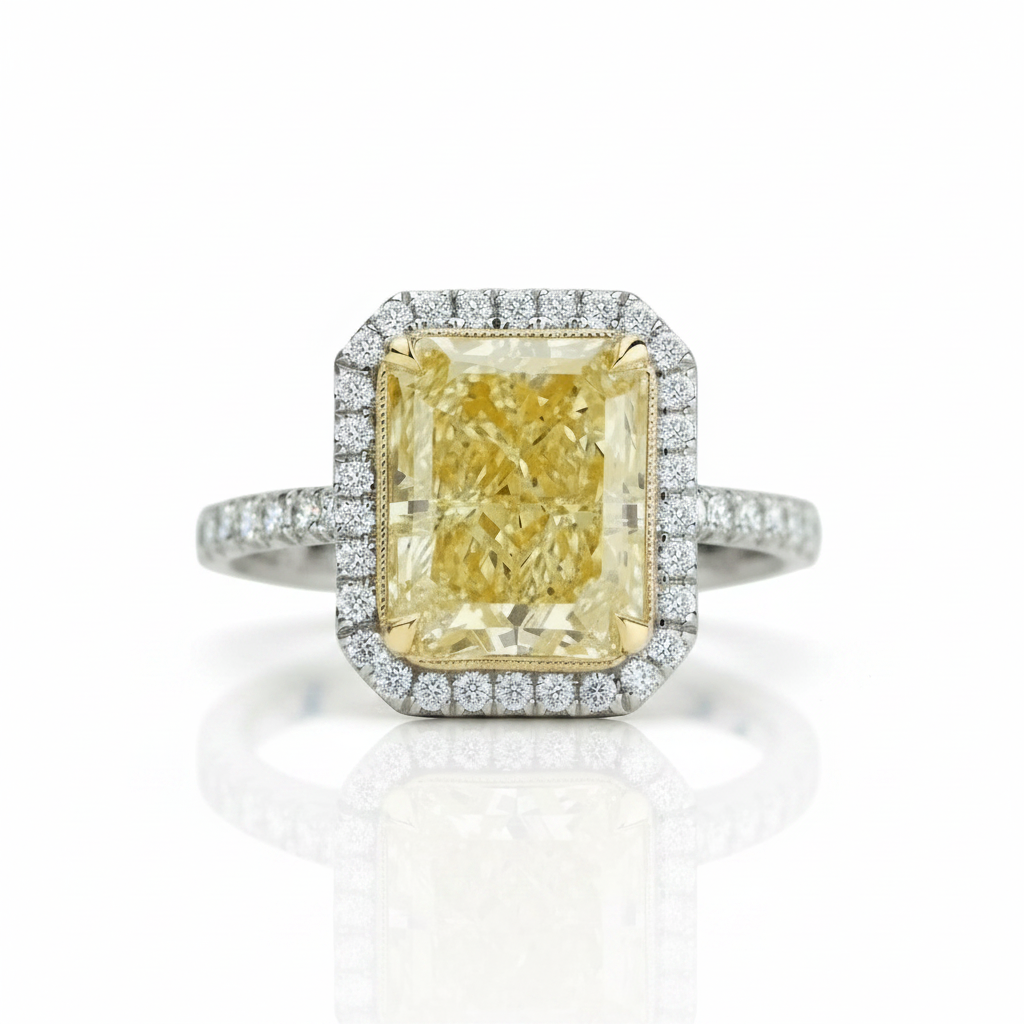 An emerald-cut yellow diamond halo ring in a silver-toned setting, featuring a diamond-paved band and a soft reflection on a white background.
