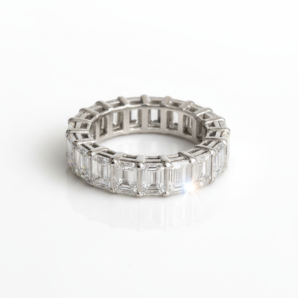 A silver eternity ring featuring baguette-cut clear gemstones, photographed on a clean white reflective surface.