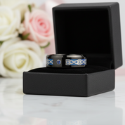 Black ring with blue accents in a black box against a floral background