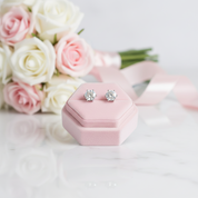Silver earrings in a pink jewelry box with pink and white roses in the background