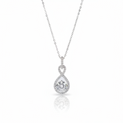 A silver pendant necklace featuring a teardrop-shaped pear-cut center stone surrounded by a halo of small round stones, suspended from a delicate silver chain on a white background with a soft reflection below.