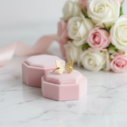 Gold butterfly ring in a pink jewelry box with flowers in the background
