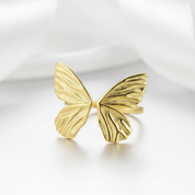 Gold butterfly-shaped ring on a white background
