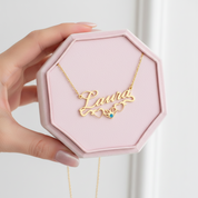 Gold necklace with 'Laura' pendant in a pink hexagonal box held by a hand.