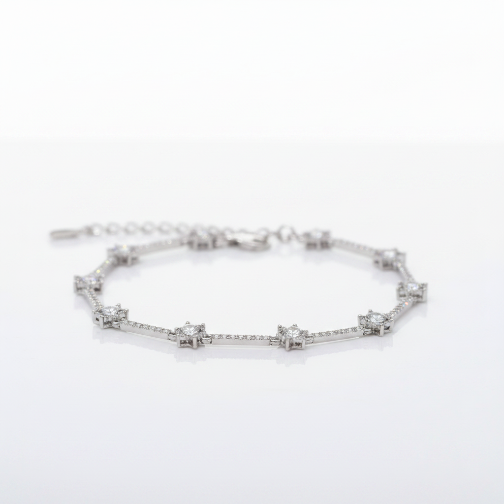 A silver-toned bracelet featuring a series of star-shaped settings with clear gemstones, displayed on a clean white reflective surface.