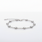 A silver-toned bracelet featuring a series of star-shaped settings with clear gemstones, displayed on a clean white reflective surface.