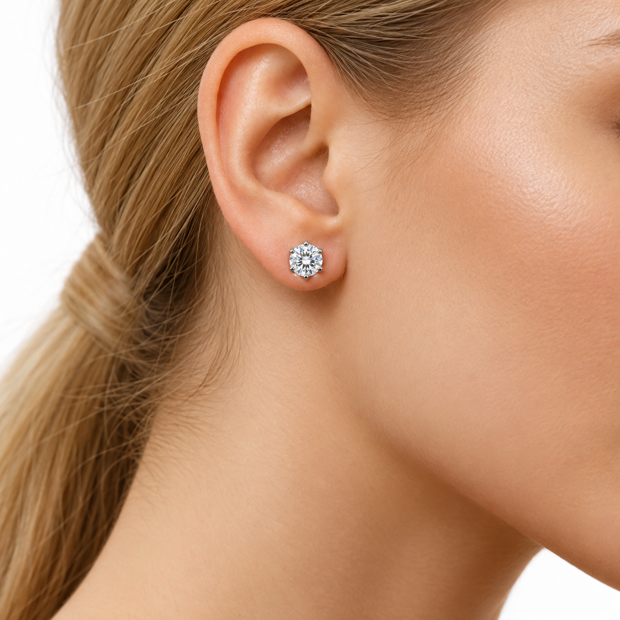 A close-up of a woman's ear wearing a single round brilliant-cut diamond stud earring in a silver setting, against a clean white background.