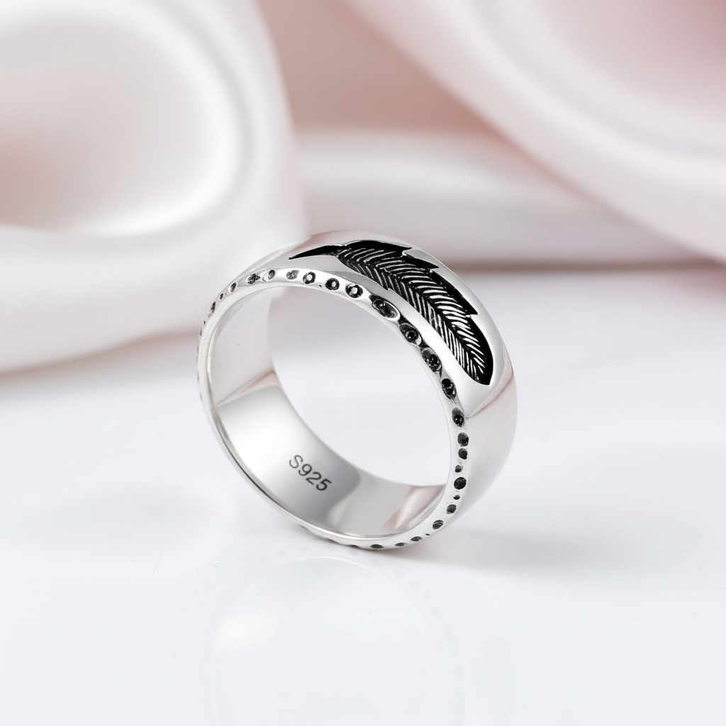 Silver ring with feather design on a white background