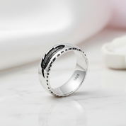 Silver ring with feather design on a white surface