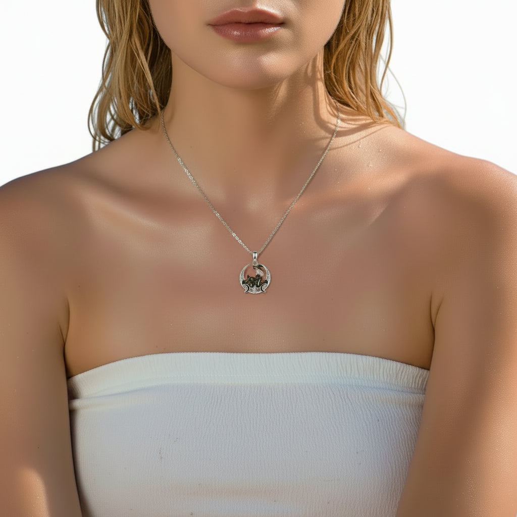 A close-up of a woman wearing a delicate silver necklace with a circular pendant featuring a small black bird, paired with a white strapless top.