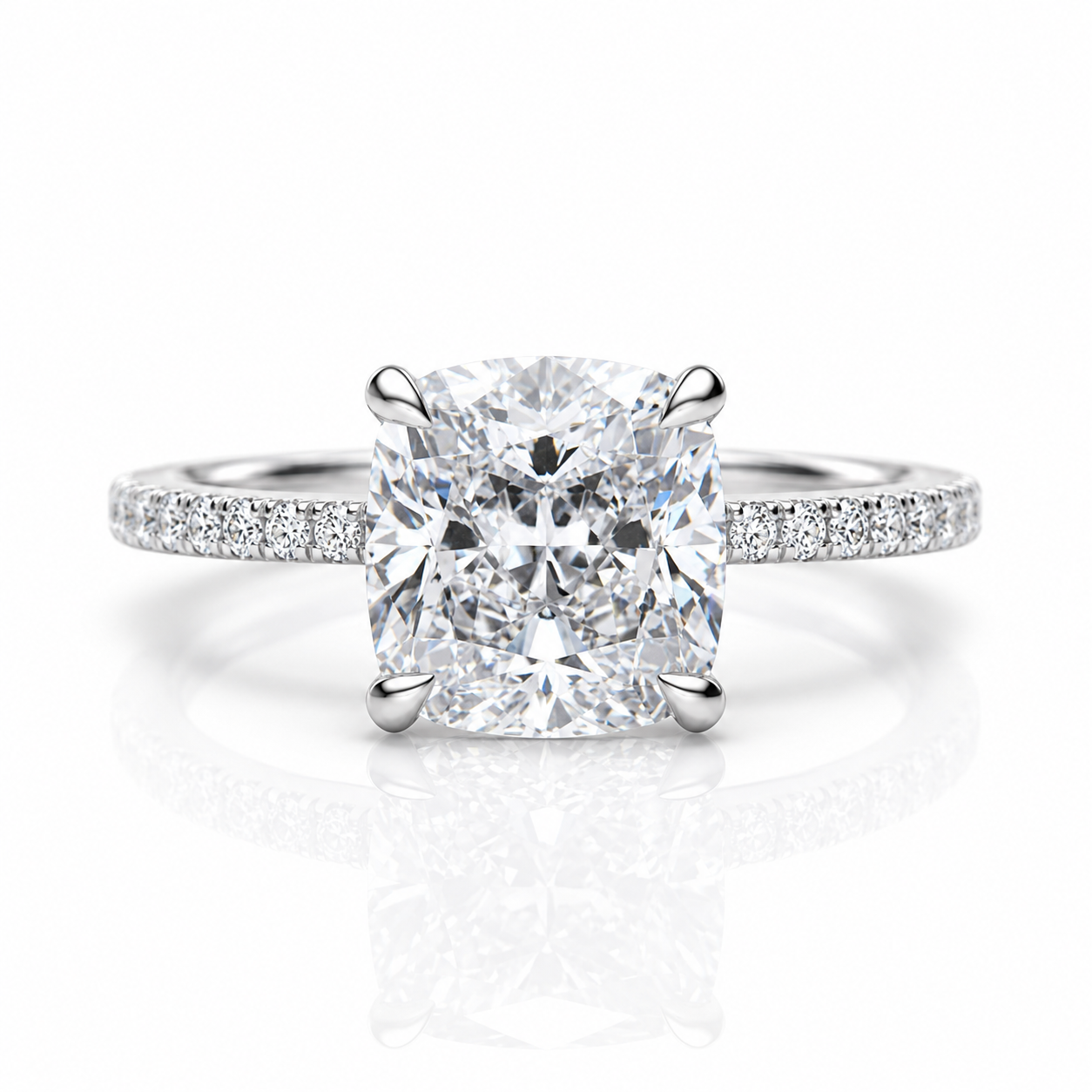 A radiant cut diamond engagement ring with a four-prong setting and a pavé band, shown on a clean white background with a soft reflection.