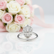 Silver ring with floral design on a white surface with pink and white roses in the background