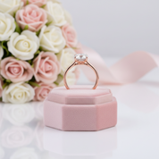 Rose gold ring on a pink velvet box with flowers in the background