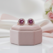 Pink gemstone earrings on a pink jewelry box with a soft floral background