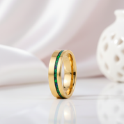 Gold ring with green inlay on a light background