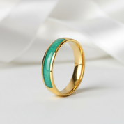 Gold ring with green inlay on a white background