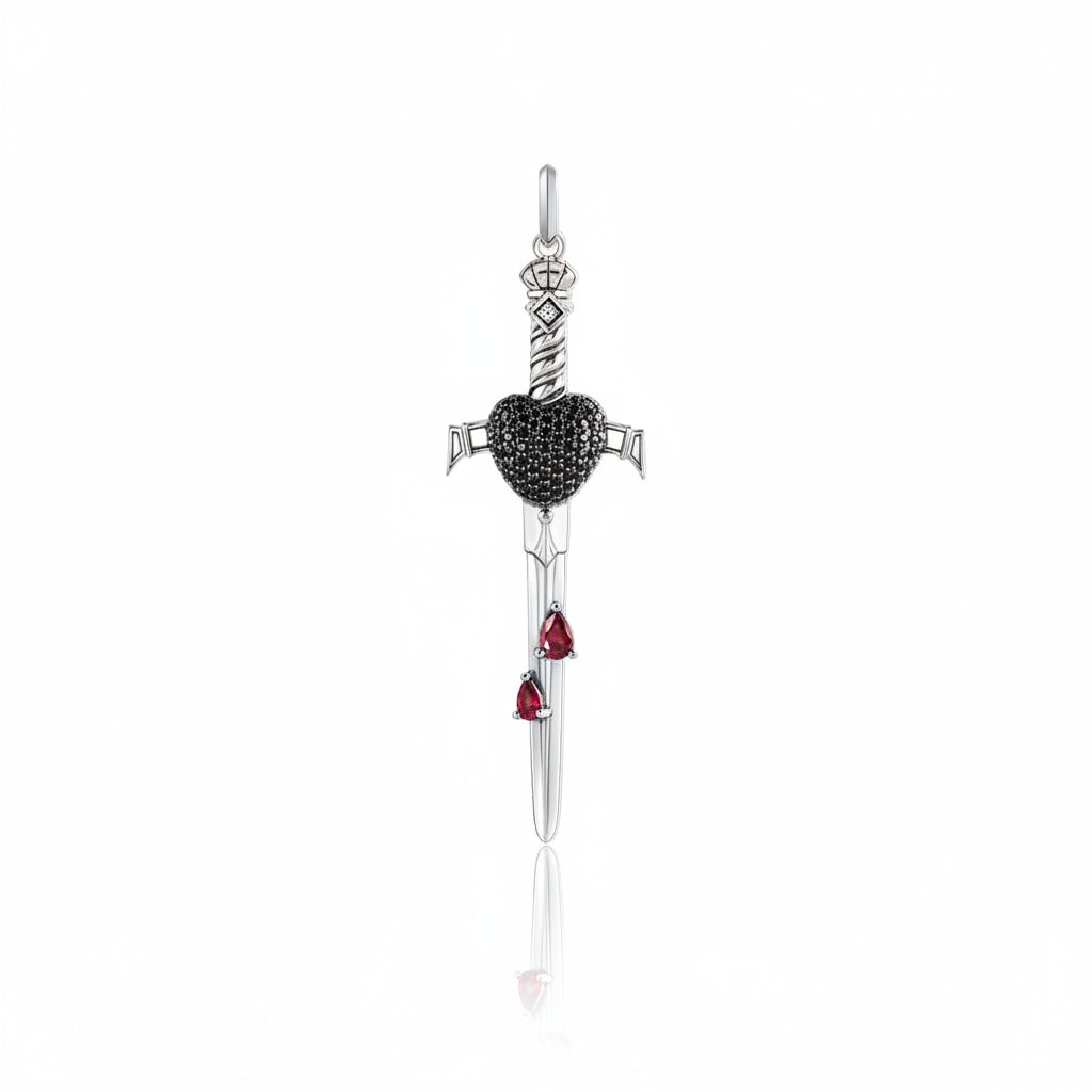 A silver dagger pendant featuring a black heart-shaped center, accented with two small red teardrop gemstones near the blade, shown on a clean white background with a soft reflection.