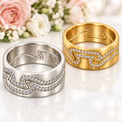 Two wavy band rings with pavé-set clear stones, shown side by side on a white reflective surface. One ring is silver-toned and the other is yellow gold-toned, both marked 925.