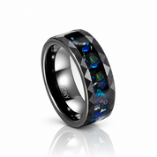 A black metallic ring with a faceted inlay of blue, green, and orange opal-like stones, shown on a clean white background with a soft reflection below.