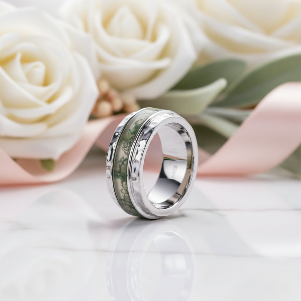 Silver ring with camouflage pattern on a reflective surface with white roses in the background