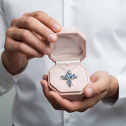 Person holding a pink jewelry box with a blue cross necklace inside